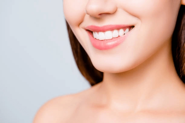 A close-up of a woman smiling with bright white teeth. -how much is a teeth whitening