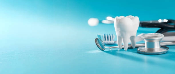 Dental tools with model tooth, toothbrush, and floss on blue background. -oral hygiene instruction